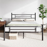 Wrought metal sleigh bed frame with geometric headboard, white mattress, and beige pillows on display.