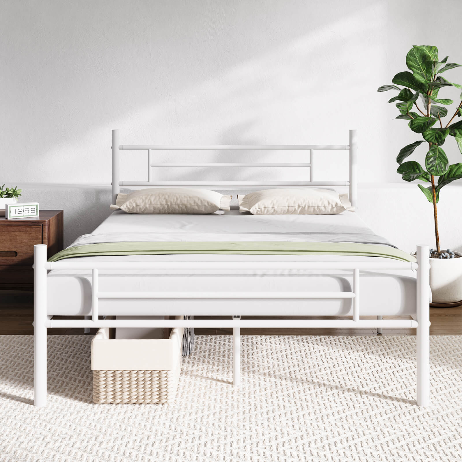 White metal bed frame with mattress, pillows, green throw, and storage basket. Modern bedroom decor.